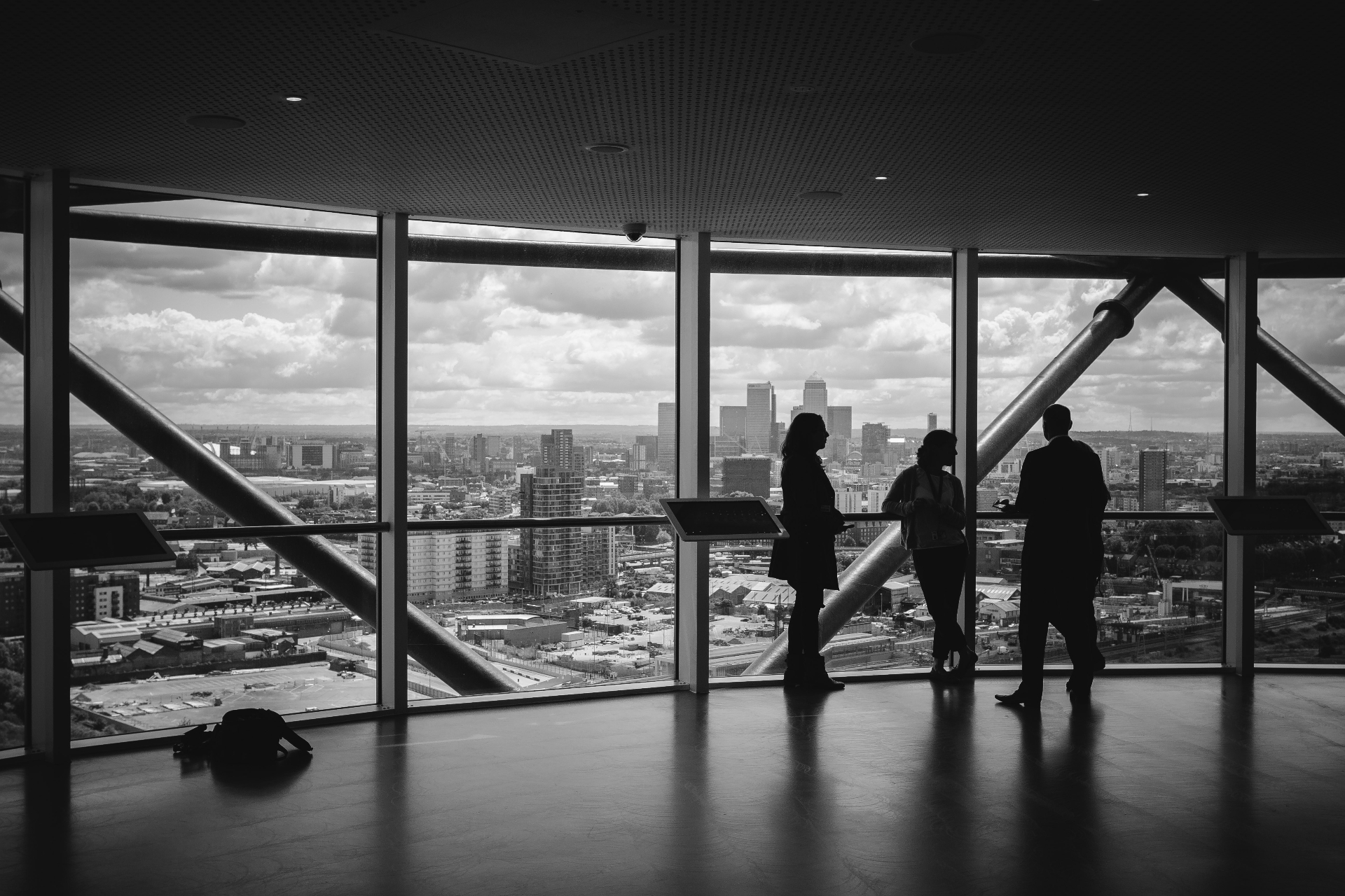 Three professionals at floor-to-ceiling windows overlooking a city skyline